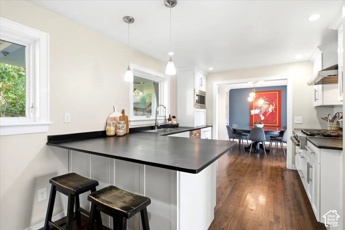 Kitchen featuring dark countertops, white cabinetry, a built-in microwave, and wood-finish flooring