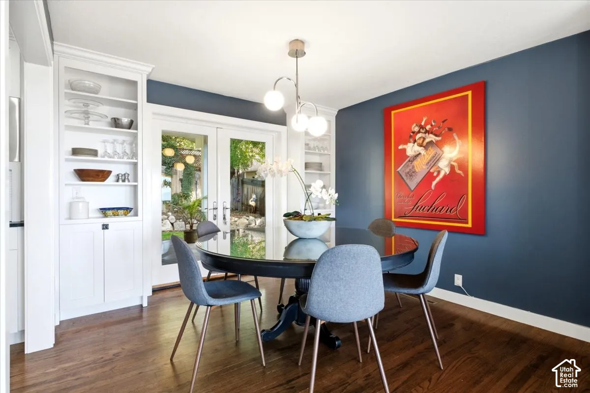 Built-in white cabinetry with open shelving, wood-finish flooring, and a modern chandelier