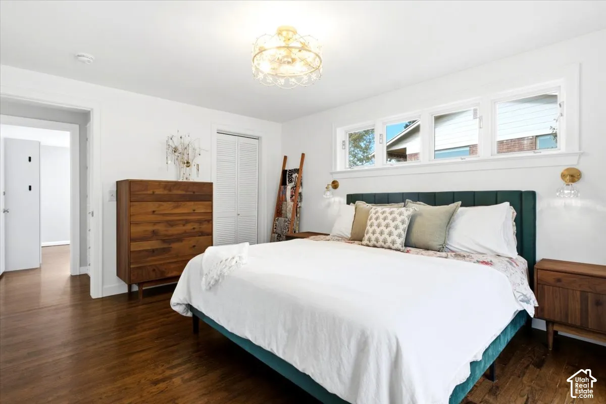Hardwood flooring, three transom windows, white walls, decorative ceiling light fixture, and white bi-fold closet doors