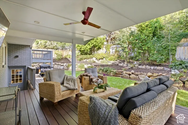 Covered outdoor living space featuring dark wood-finish decking, recessed lighting, and a ceiling fan