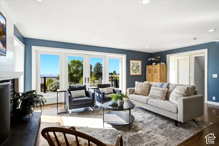 Bright living area with wood-finish flooring, a fireplace with a stone surround, recessed lighting, and a multi-panel glass door leading to an exterior balcony