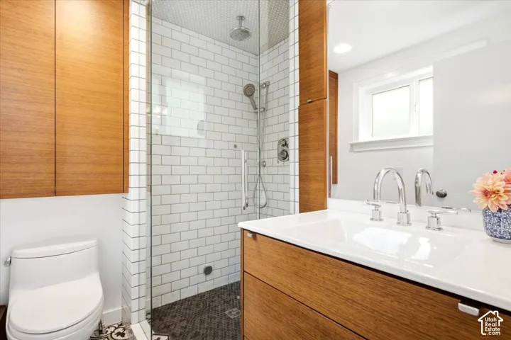 Glass-enclosed shower with subway tile surround and dark stone mosaic flooring
