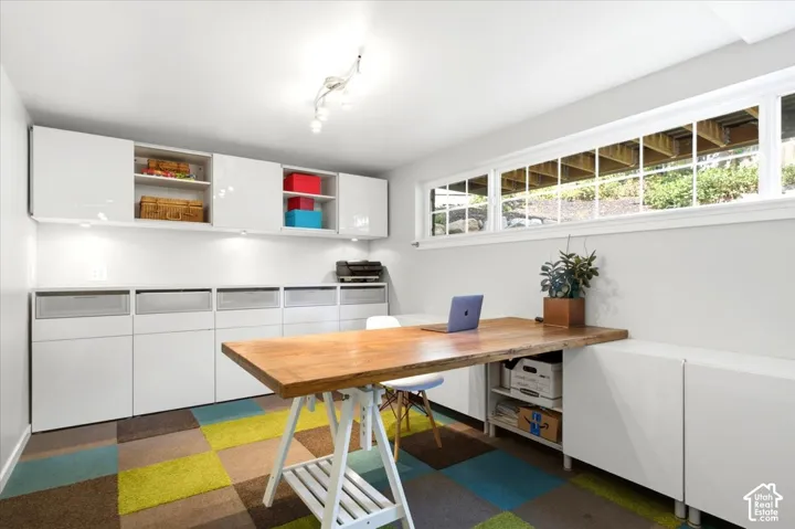 Built-in cabinetry and shelving, track lighting, wood-finish desktop, and multi-paned horizontal window