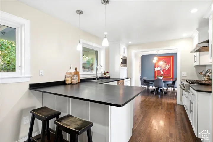 Kitchen featuring dark countertops, white cabinetry, a built-in microwave, and wood-finish flooring