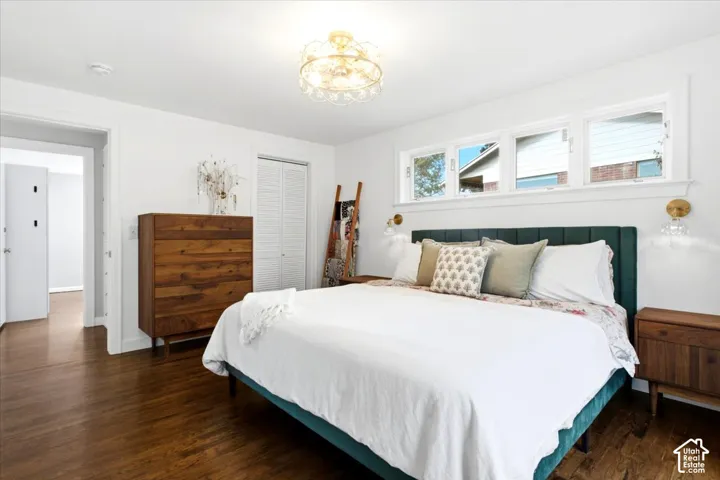 Hardwood flooring, three transom windows, white walls, decorative ceiling light fixture, and white bi-fold closet doors