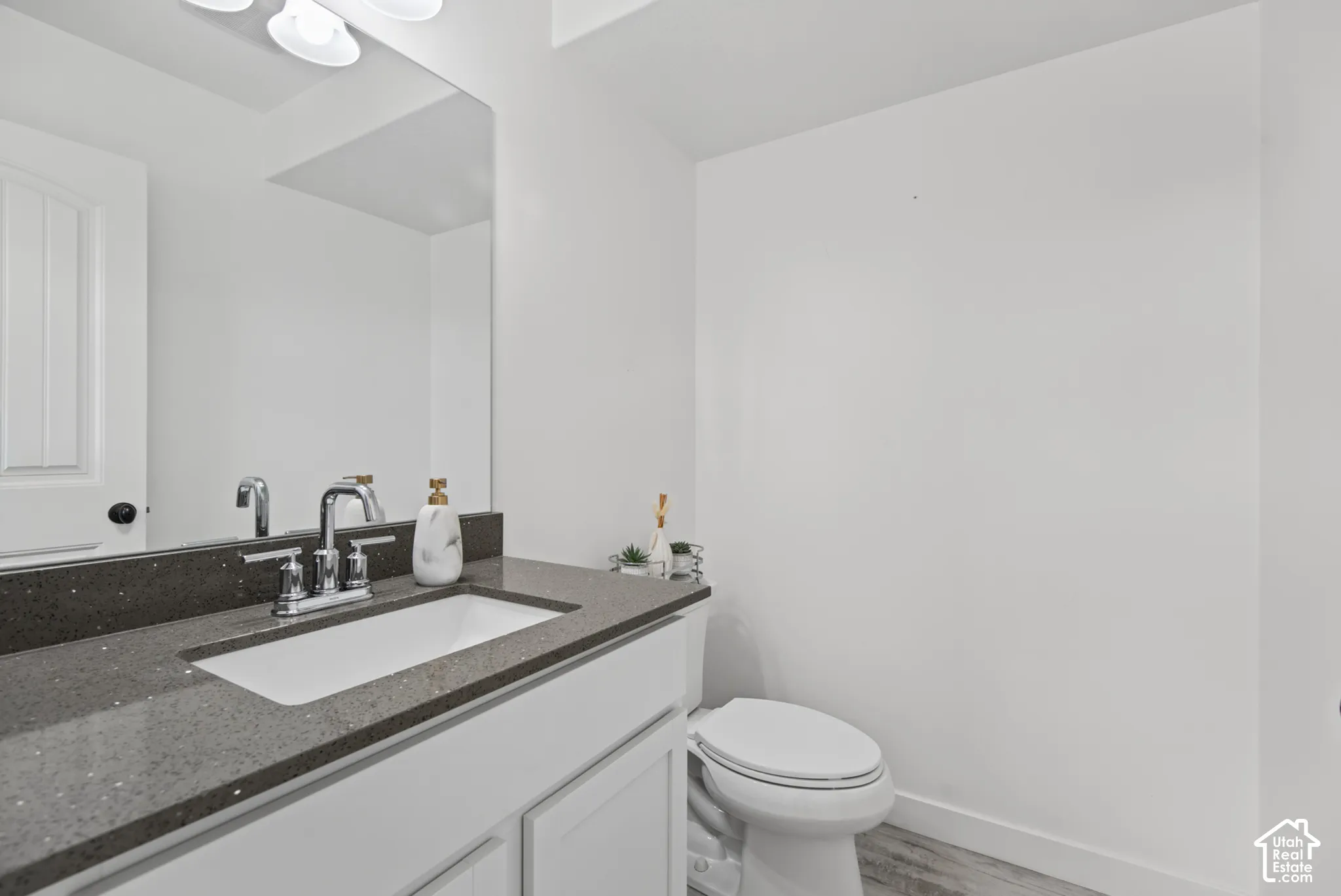 Vanity with a dark quartz-finish countertop, undermount sink, chrome faucet, and white cabinetry