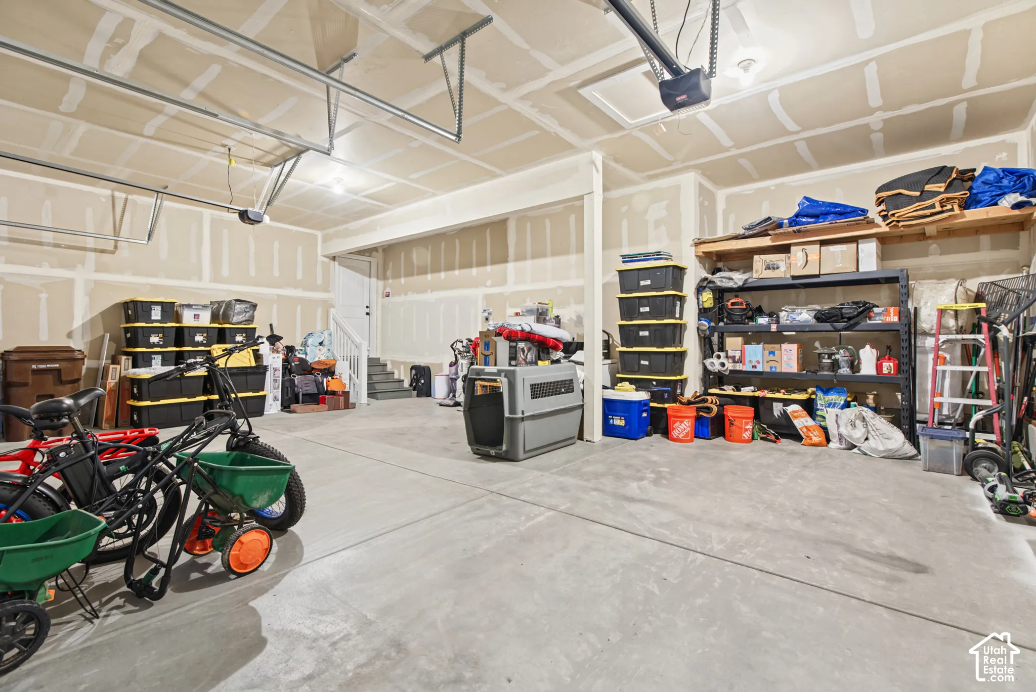 Large garage space with a concrete floor, exposed drywall walls, and overhead lighting
