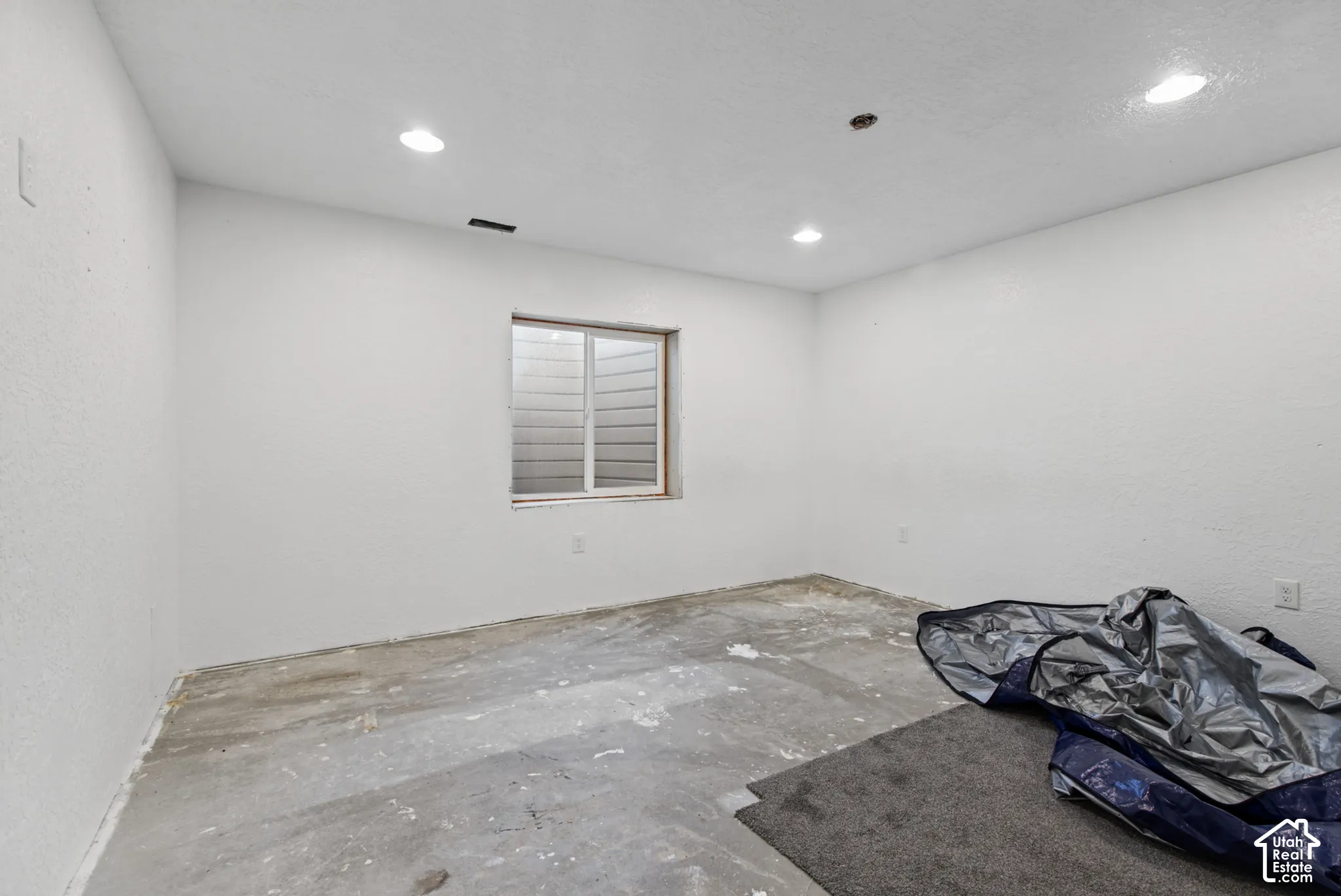 Recessed ceiling lighting, white painted walls, and a single window