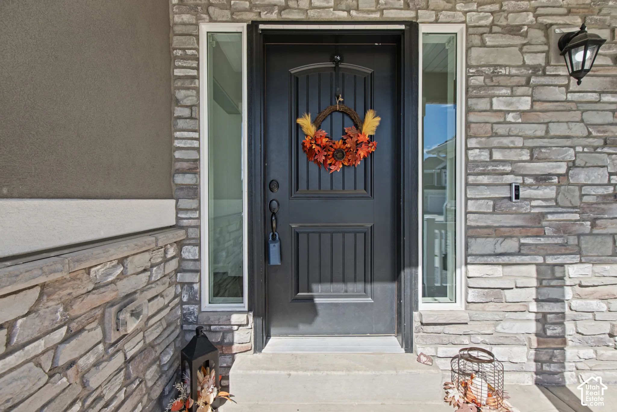 Stone veneer exterior with stucco accents, paneled entry door, and integrated sidelight windows