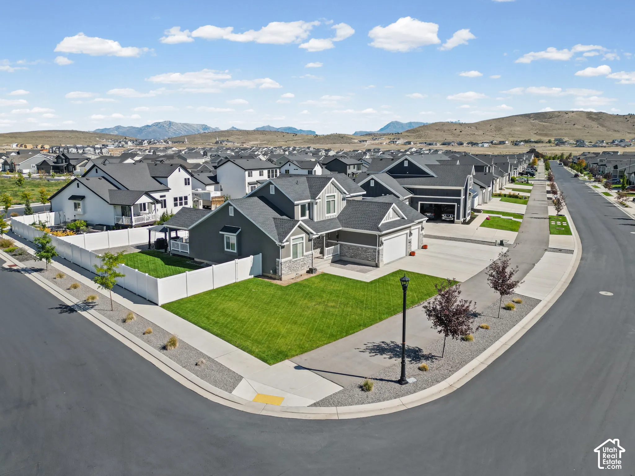 Corner lot residence featuring a well-maintained lawn, a two-car garage, and a covered porch