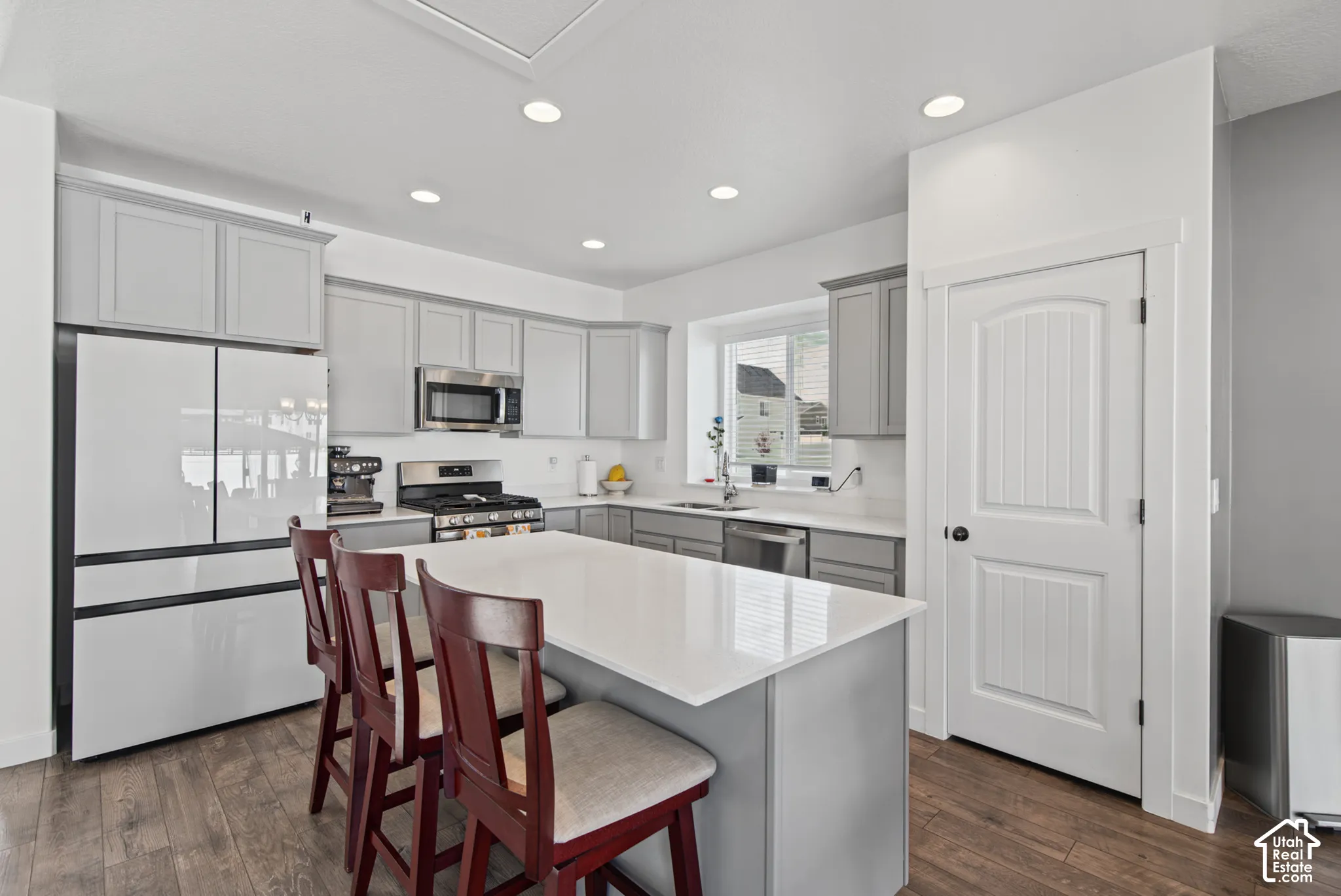 Kitchen featuring light gray cabinetry, white countertops, stainless steel appliances, and wood-finish flooring