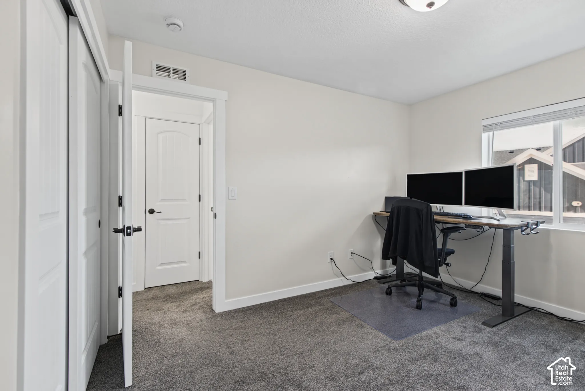 Carpeted room featuring a window with horizontal blinds, white trim, and a ceiling light fixture