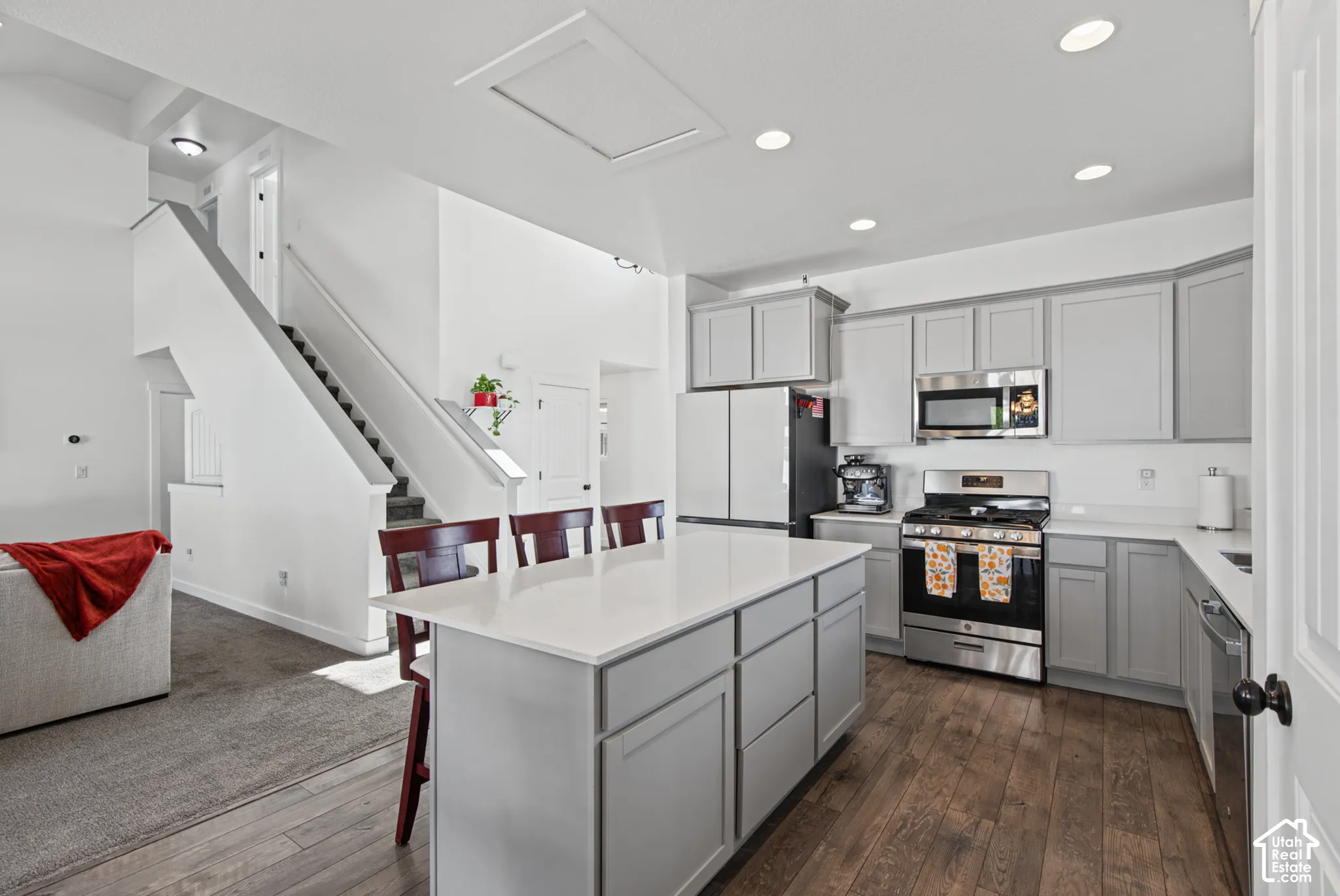 Kitchen featuring an integrated island with countertop seating, stainless steel appliances, light gray cabinetry, and recessed lighting