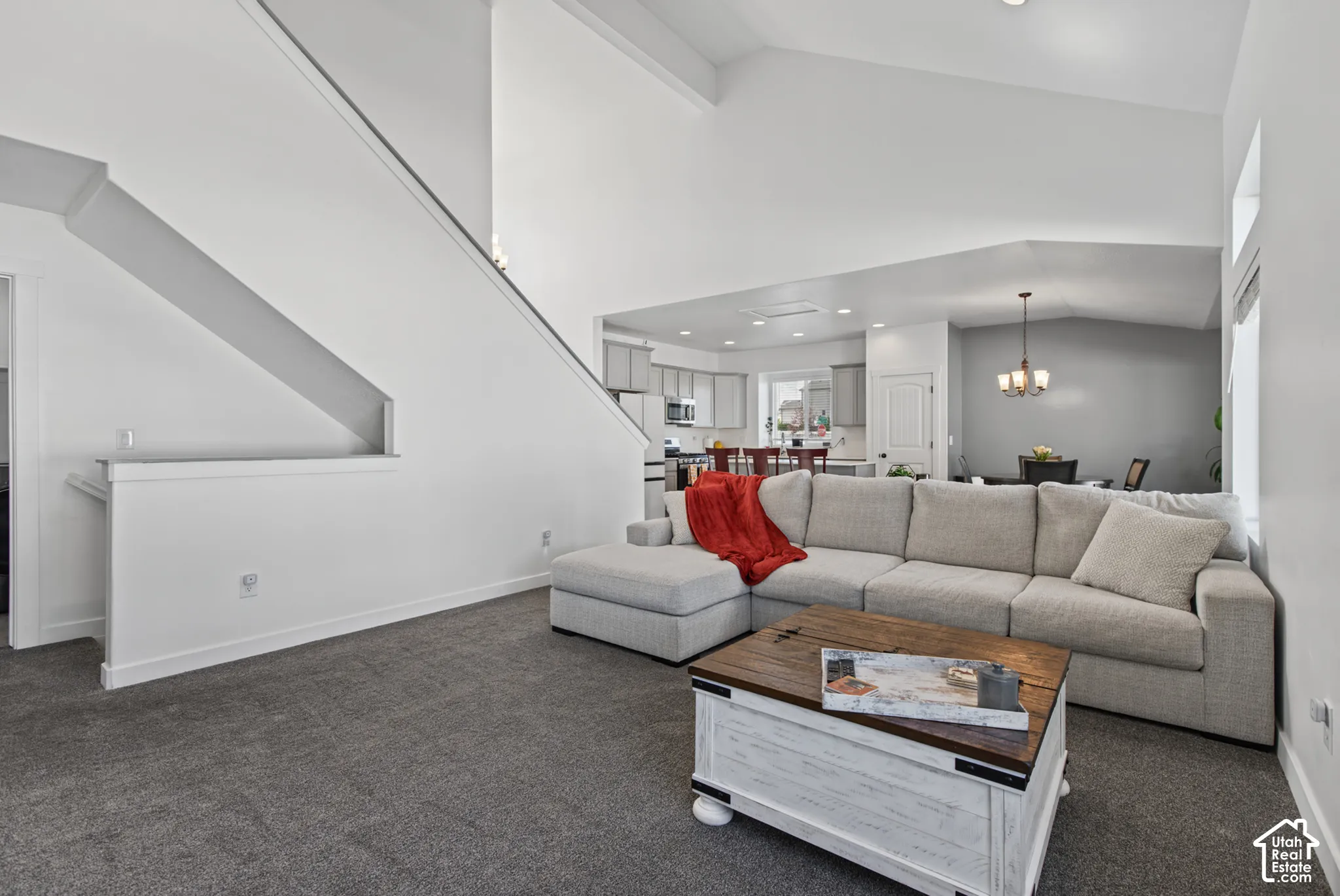 Vaulted ceilings with recessed lighting, carpeted flooring, and a staircase with a partial wall railing