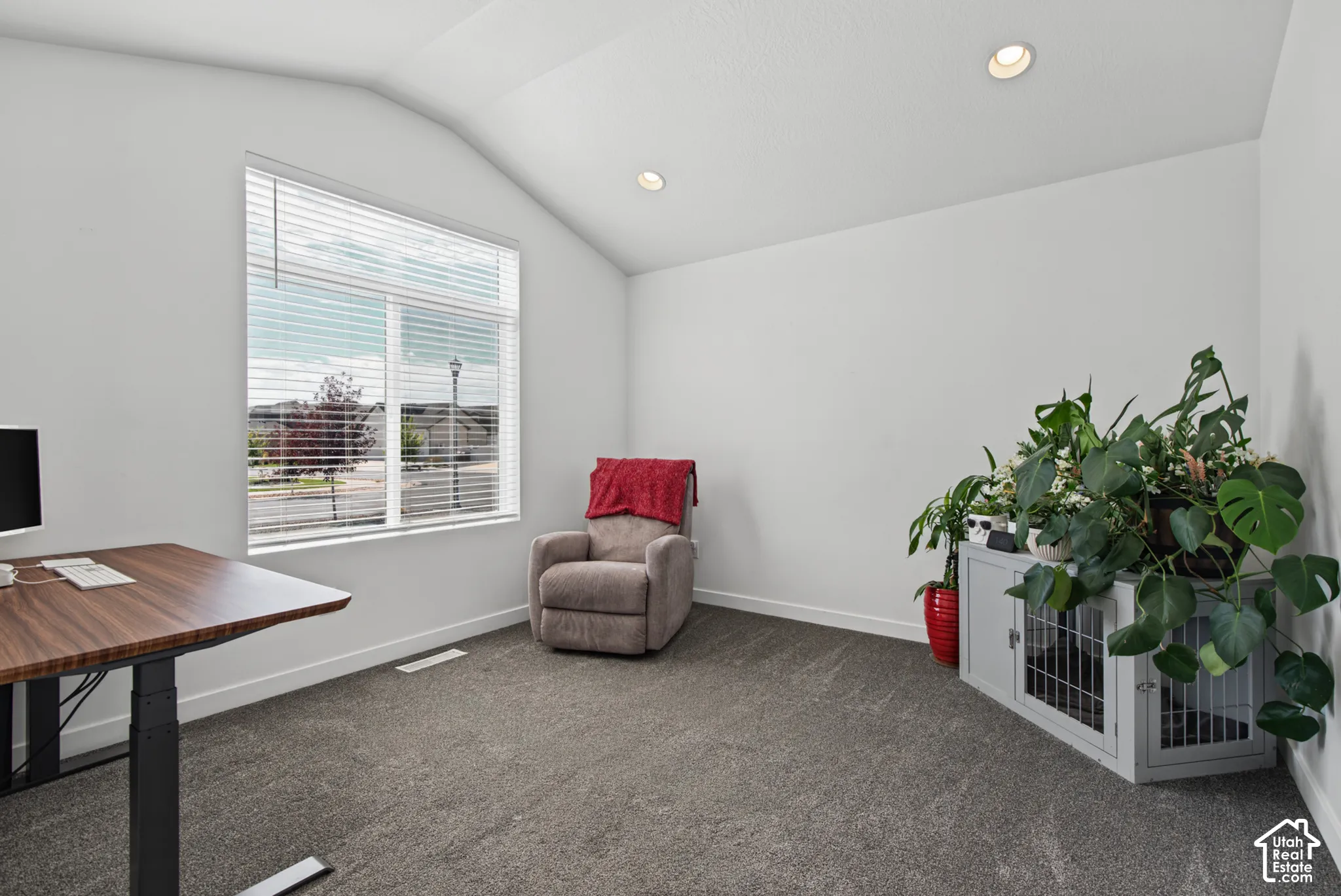Vaulted ceiling, recessed lighting, large window with blinds, and neutral wall paint