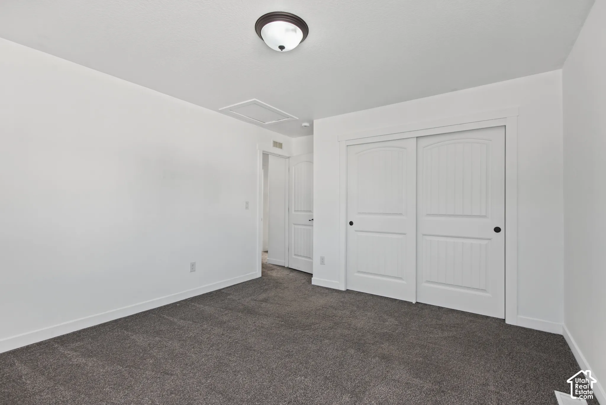 Neutral gray carpet with white baseboards, white walls, and a ceiling-mounted light fixture