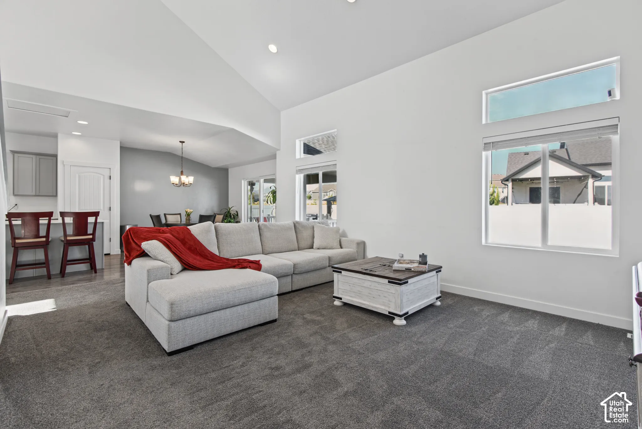 Spacious living area featuring vaulted ceilings, recessed lighting, large windows, and neutral carpeting