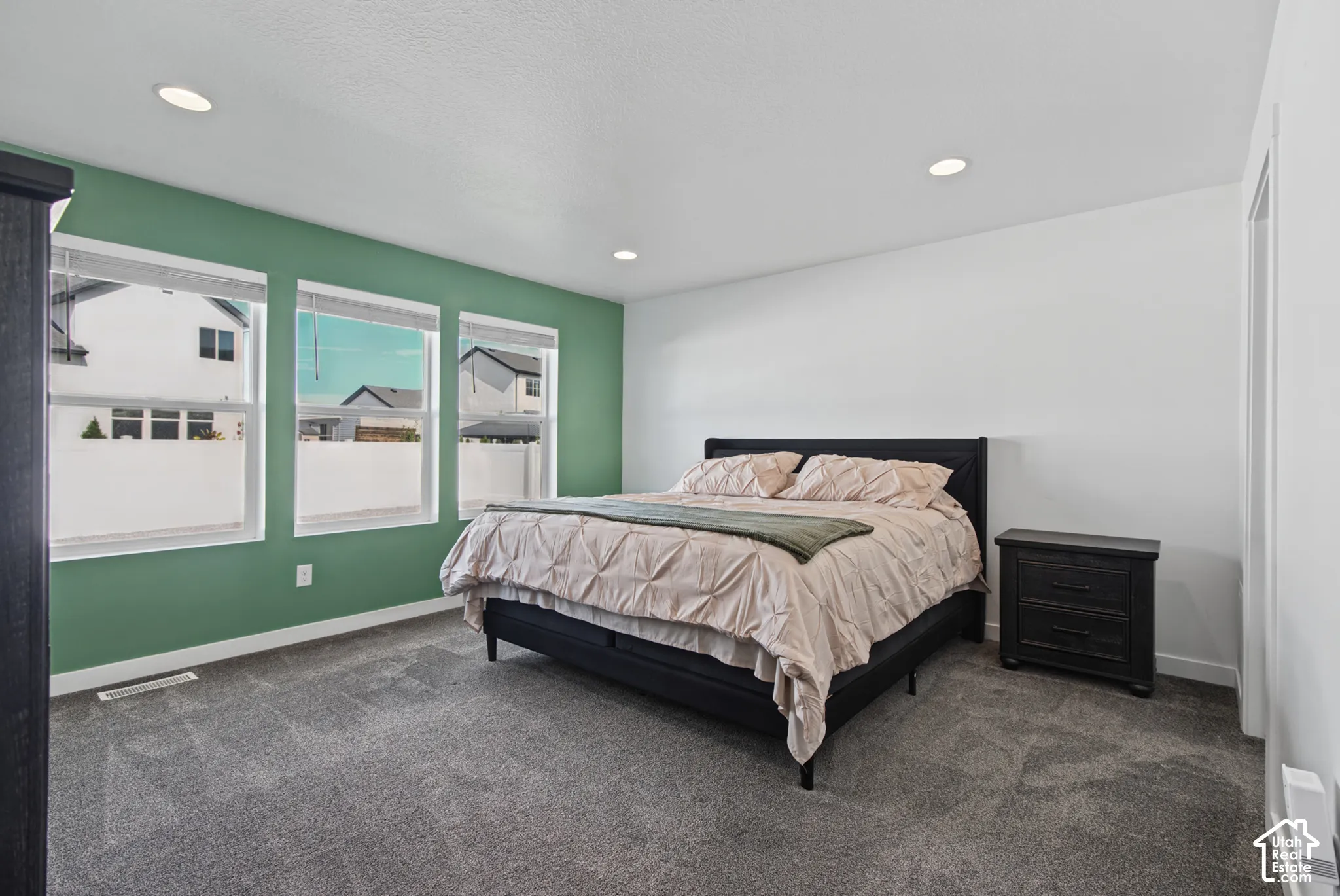 Recessed lighting, three windows with blinds, and wall-to-wall carpeting