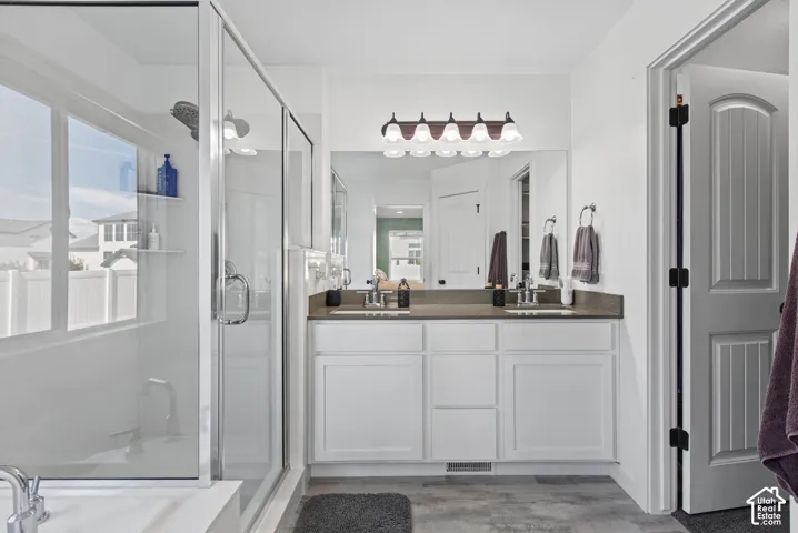 Double vanity with an integrated mirror and sconce lighting, glass-enclosed shower, and a built-in bathtub