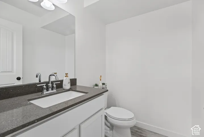 Vanity with a dark quartz-finish countertop, undermount sink, chrome faucet, and white cabinetry