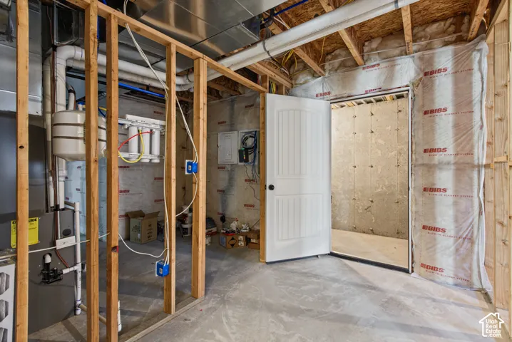 Unfinished basement with exposed wood framing, concrete flooring, and an interior door