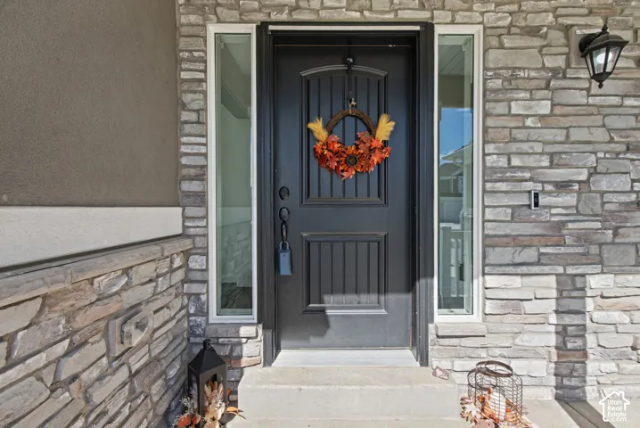 Stone veneer exterior with stucco accents, paneled entry door, and integrated sidelight windows