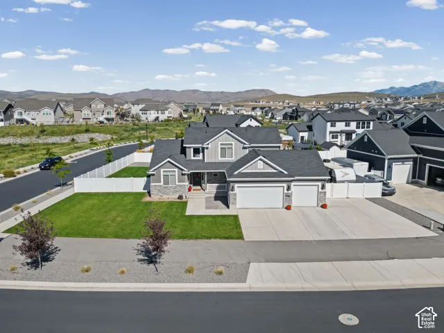 Contemporary-style property with a two-car garage, gray siding, stone accents, and a white privacy fence