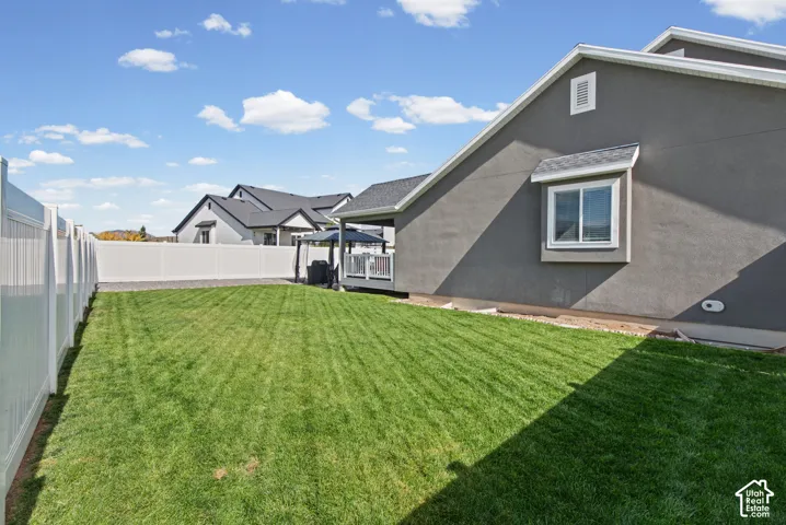 Expansive lawn area with a white privacy fence, and a stucco exterior
