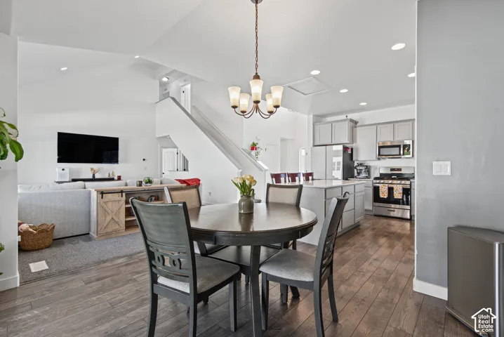 Open-concept living space featuring wood-finish flooring, vaulted ceilings, recessed lighting, and a modern kitchen with stainless steel appliances