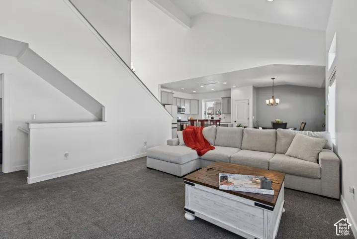 Vaulted ceilings with recessed lighting, carpeted flooring, and a staircase with a partial wall railing