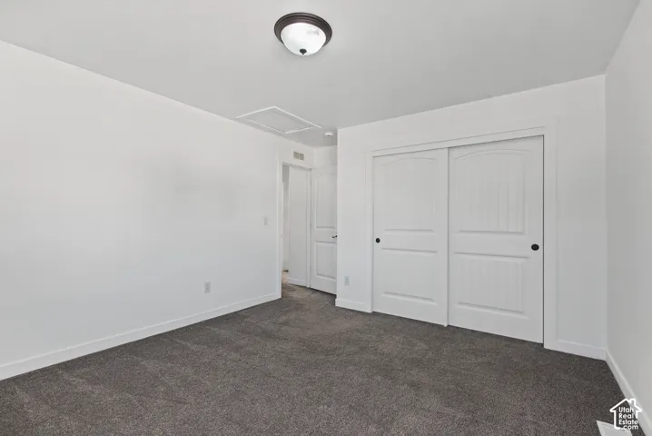Neutral gray carpet with white baseboards, white walls, and a ceiling-mounted light fixture