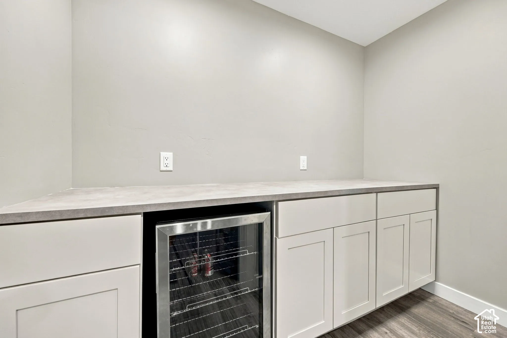 Built-in beverage refrigerator, light-toned cabinetry, light-toned countertop, and wood-finish flooring