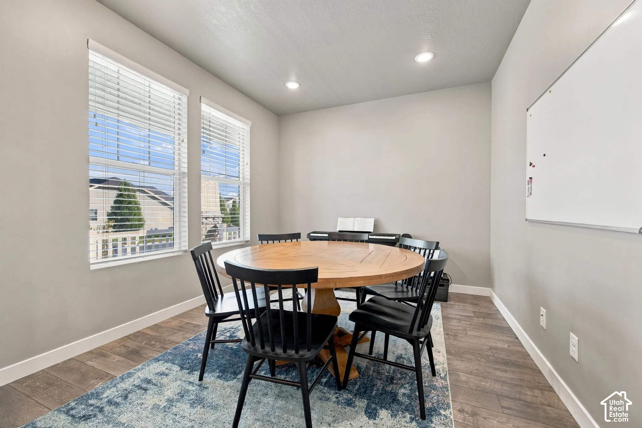 Two large windows with blinds, recessed lighting, and wood-finish flooring