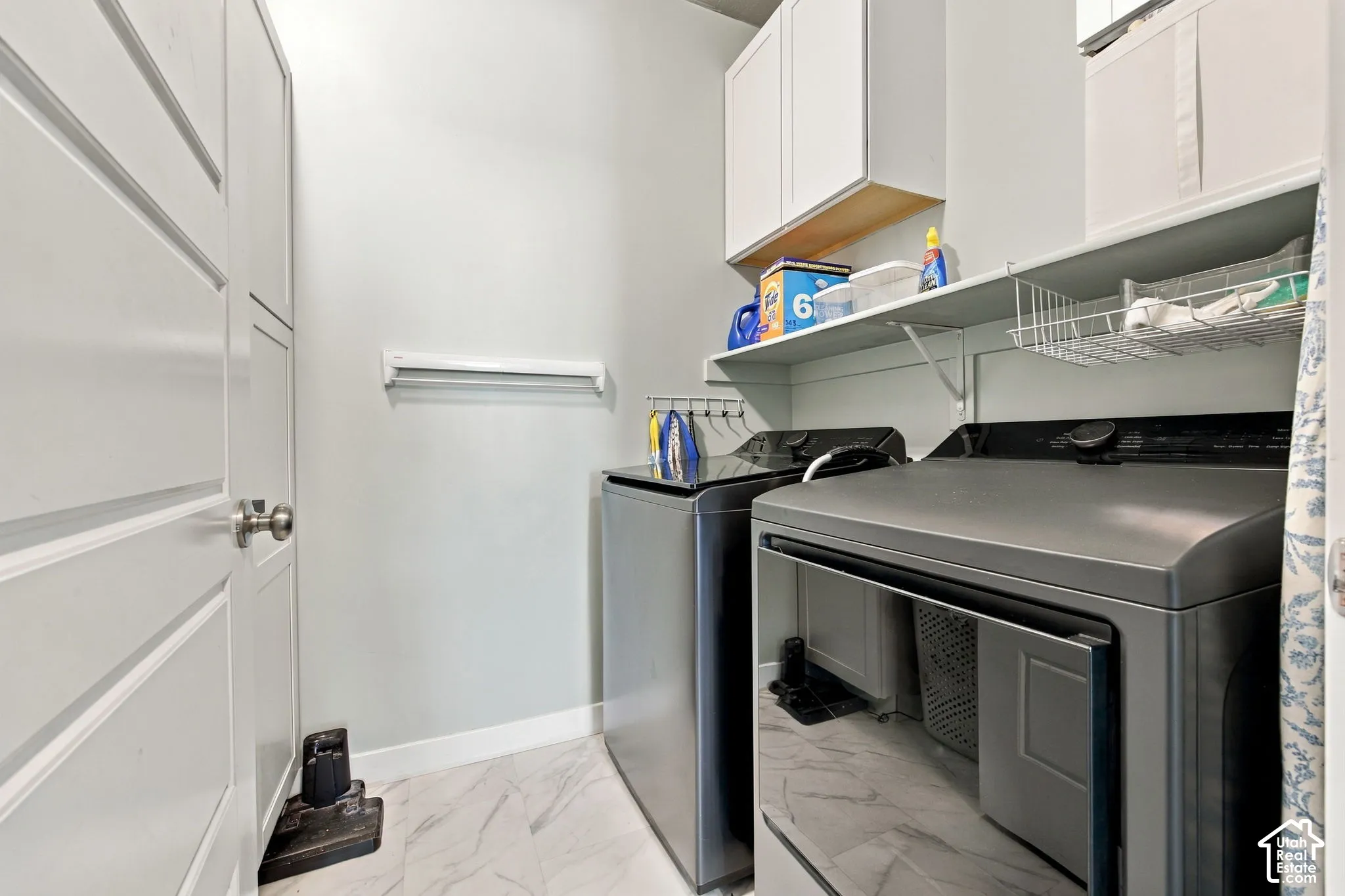 Built-in overhead white cabinetry, integrated shelving, and marble-look tile flooring
