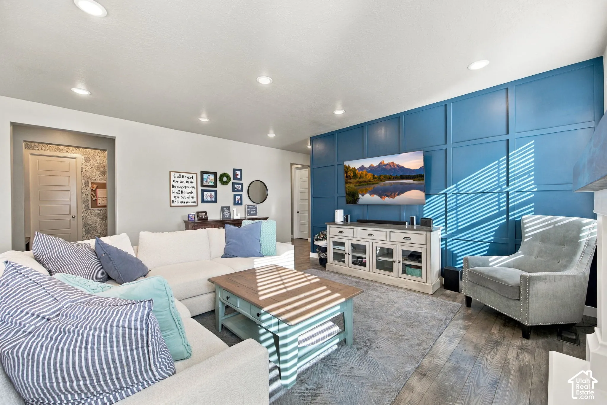 Recessed lighting illuminates the open living area featuring a prominent blue accent wall with decorative paneling