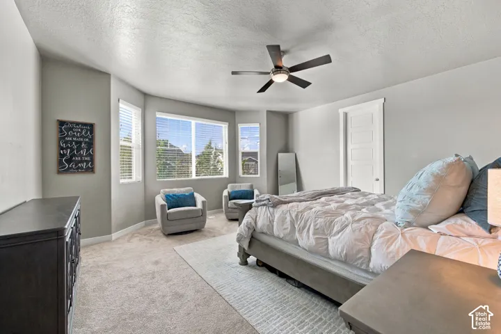 Primary - Expansive room featuring carpet flooring, bay windows, and a ceiling fan