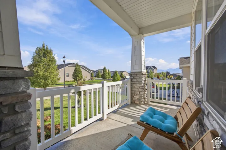 Covered front porch with stone and siding accents, white railing, and concrete flooring