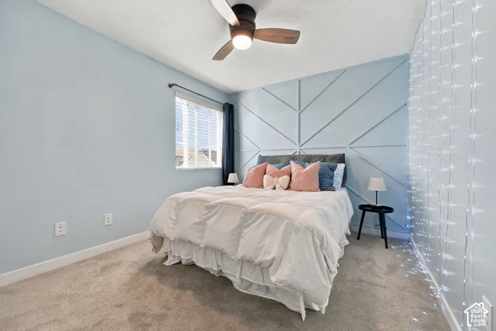 Bedroom 2 - Patterned accent wall, neutral carpet, window with blinds, ceiling fan with integrated lighting
