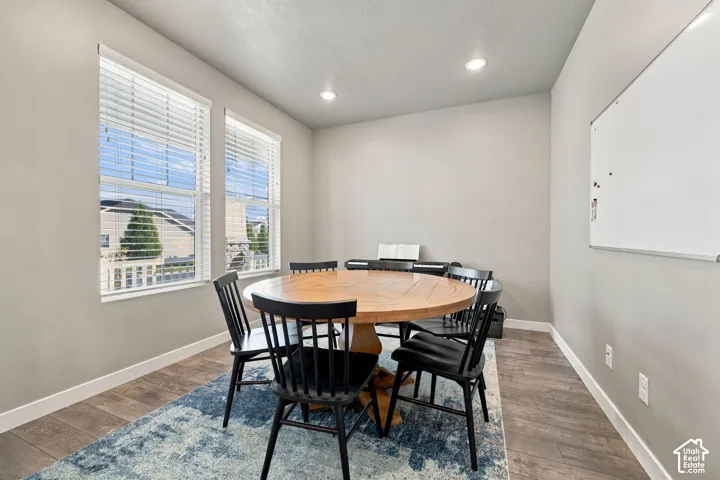 Two large windows with blinds, recessed lighting, and wood-finish flooring