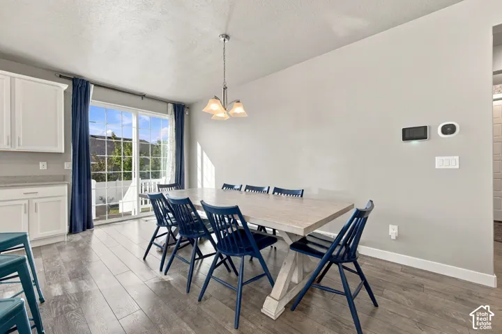Sliding glass door to the exterior, wood-finish flooring, recessed lighting, pendant light fixture, and white cabinetry with a light-toned countertop
