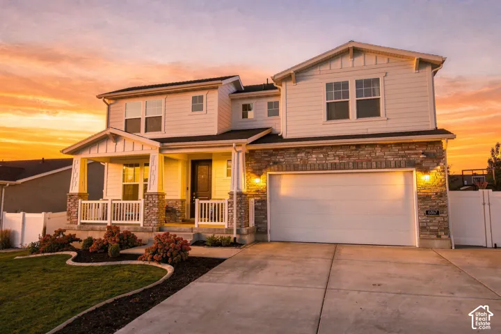 Two-story exterior with siding and stone accents, featuring a covered front porch, an attached two-car garage, and a concrete driveway