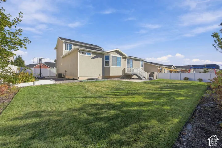 Expansive backyard featuring a manicured lawn, white vinyl fencing, and a multi-level deck with white railings