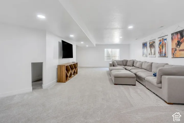 Recessed ceiling lighting, light gray carpeting, neutral wall color, built-in wooden shelving, and a horizontal window with blinds