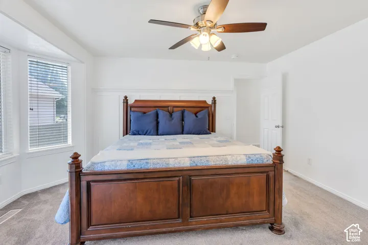 Recessed bay window, ceiling fan, wainscoting, white interior door, and carpet flooring