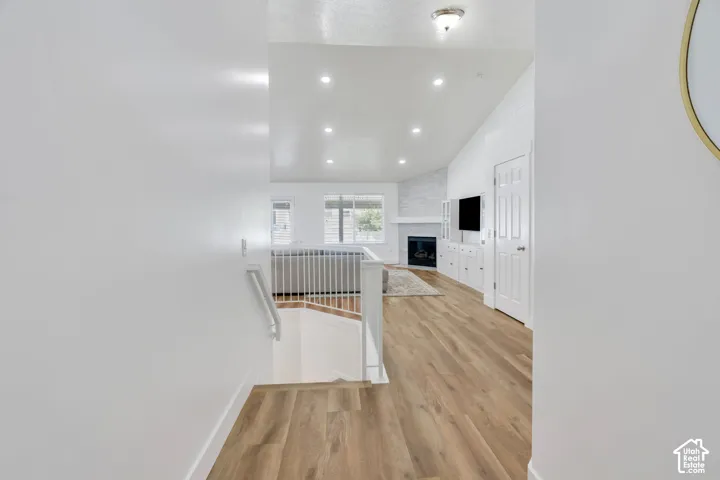 Wood-finish flooring, recessed lighting, and a white railing create a bright, open space