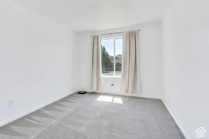 Window with natural light, neutral wall paint, gray carpet, and white trim