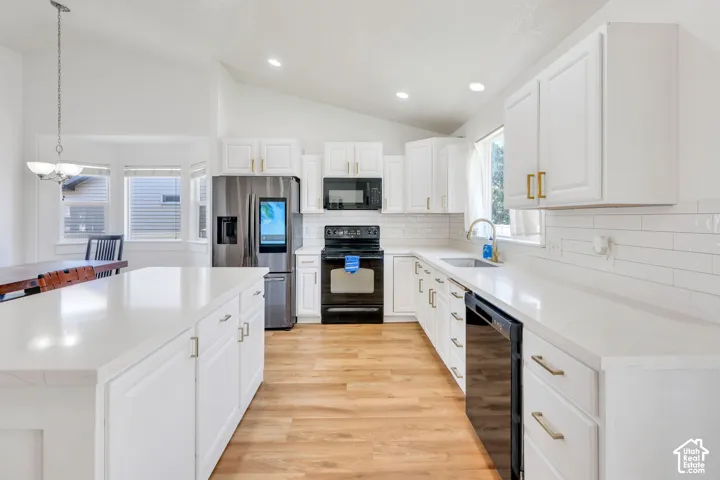 Kitchen featuring white cabinetry, light countertops, wood-finish flooring, stainless steel refrigerator, and recessed lighting