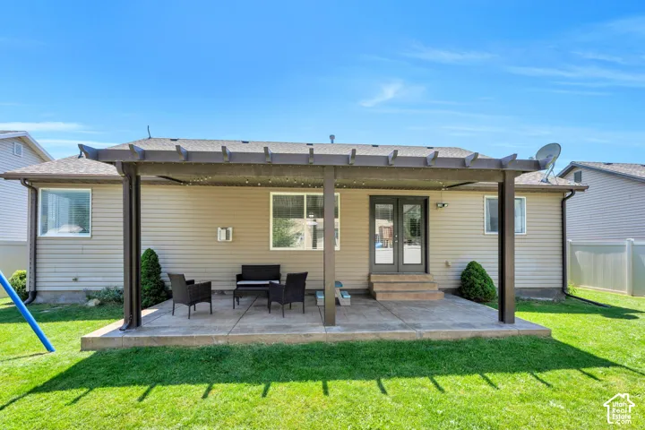 Private backyard with a concrete patio, a pergola, and green lawn space