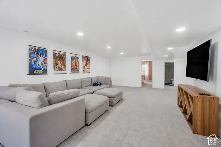 Recessed lighting, wall-mounted television, and light gray carpeting