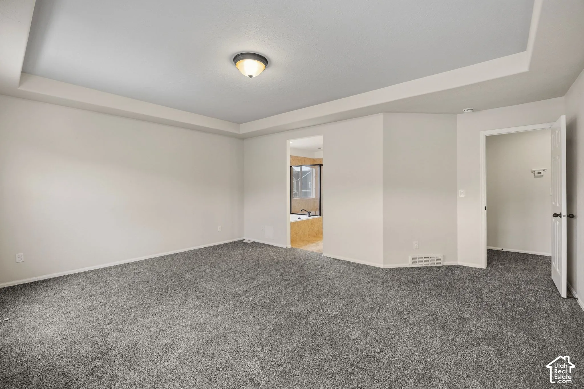 Primary bedroom with ray ceiling, recessed lighting, neutral wall tones, carpeting and ensuite